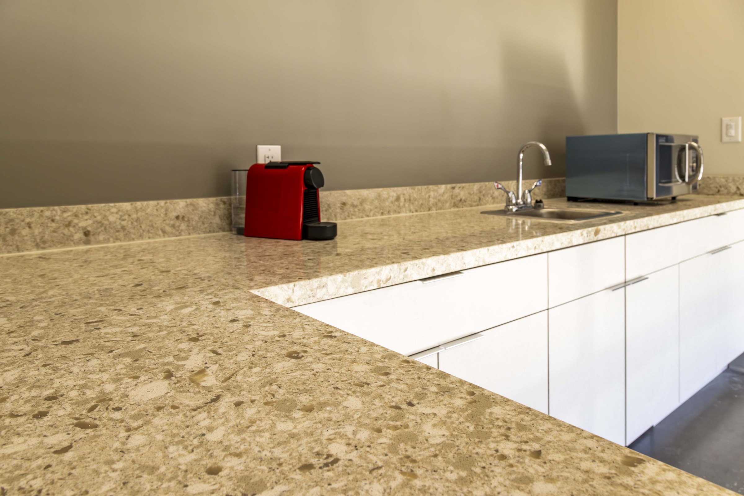 Finished quartz breakroom counter with sink, microwave, and coffee maker at Moen HQ office.