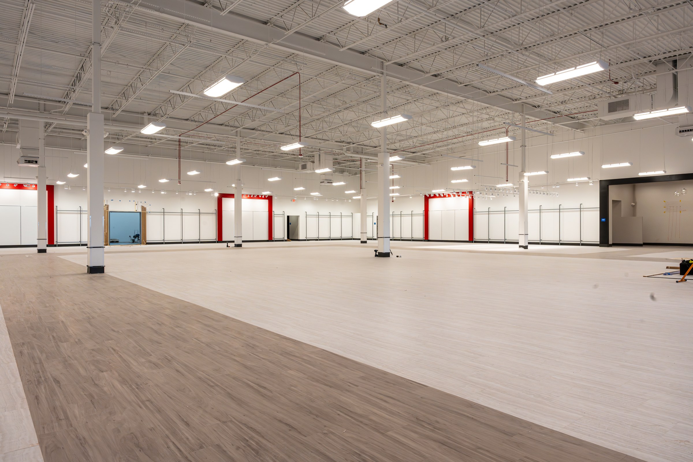Wide view of the empty TJ Maxx sales floor with new wood-look vinyl flooring and red accent walls.