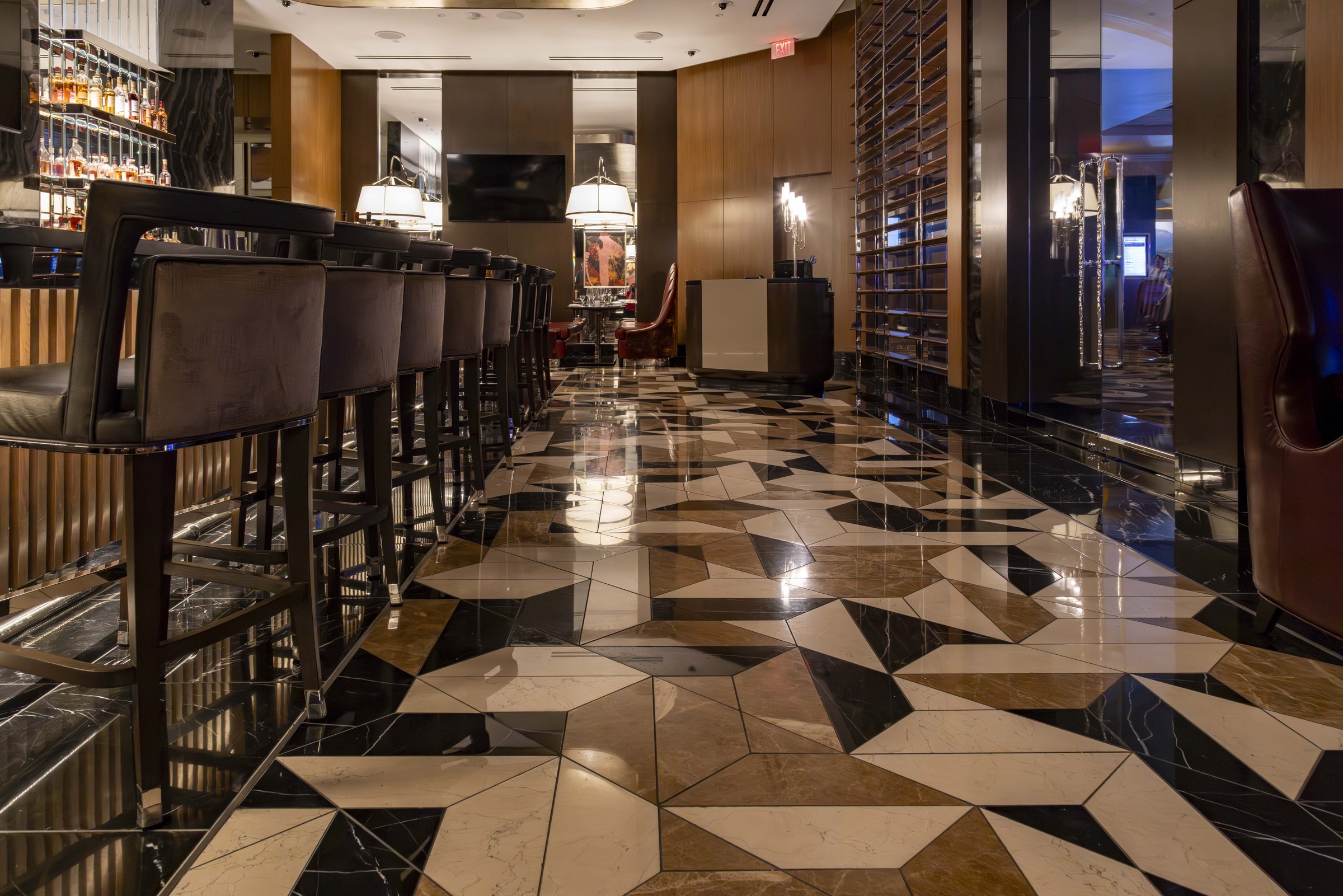 Close angle on the finished marble mosaic bar floor with black and beige geometric tile shapes.